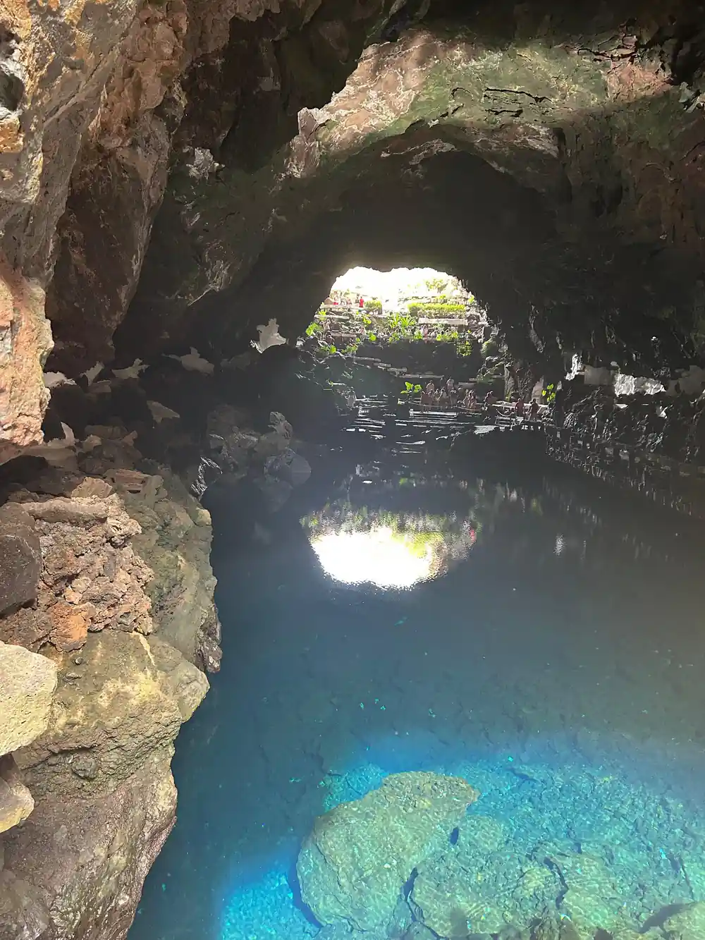 Cave pool with glowing green mineral deposits and stone walls