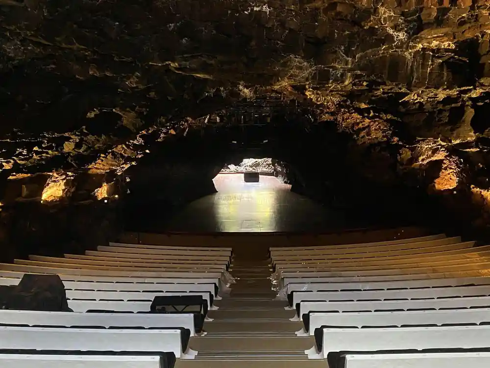 Cave with wooden benches facing bright opening and water