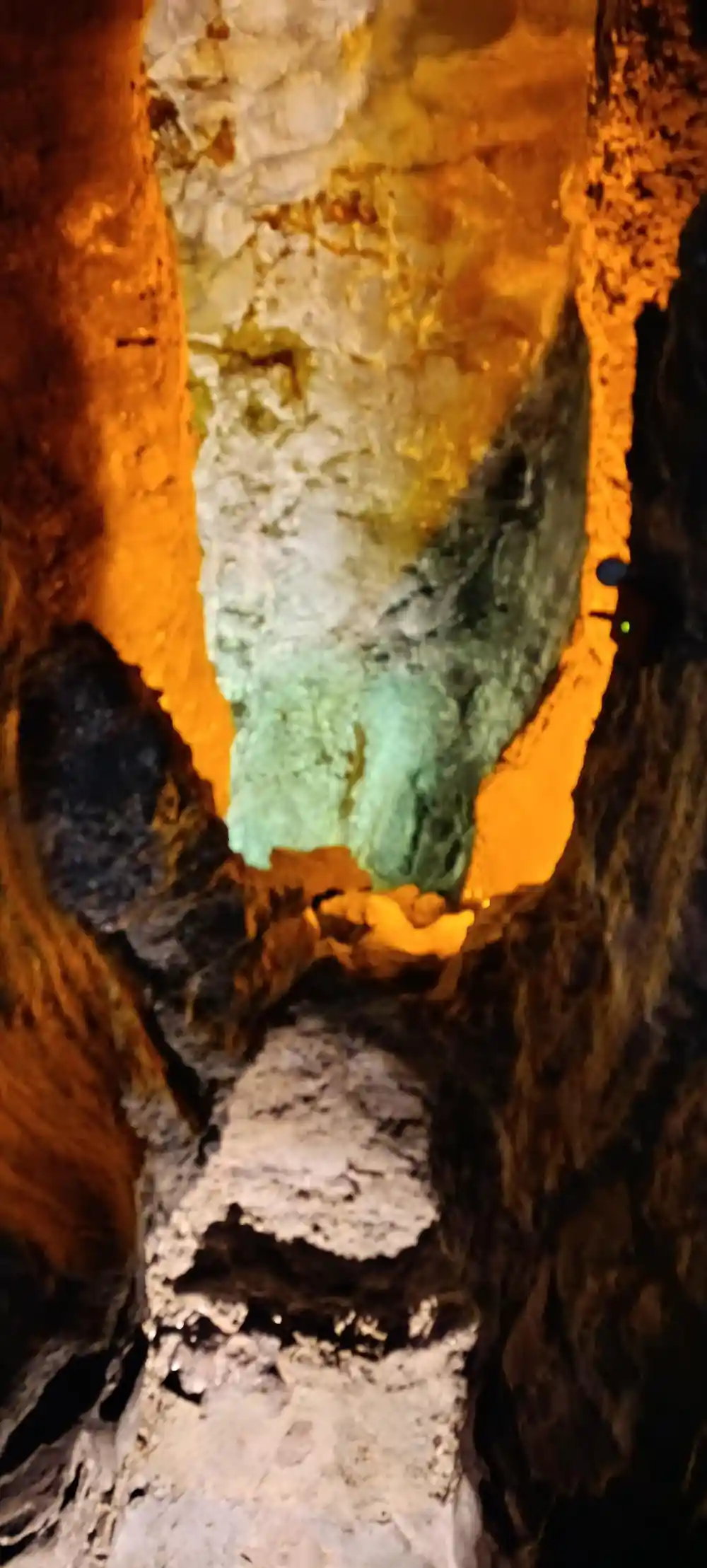 Dark cave interior with glowing orange and green mineral deposits