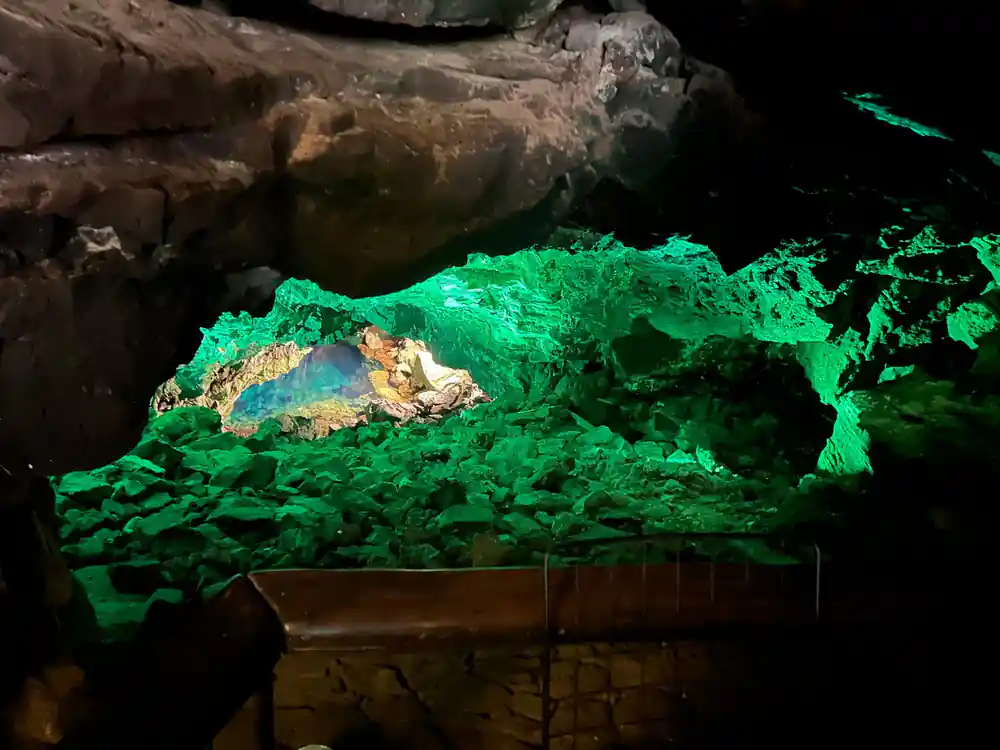 Dark cave tunnel opening to bright reflective pool water