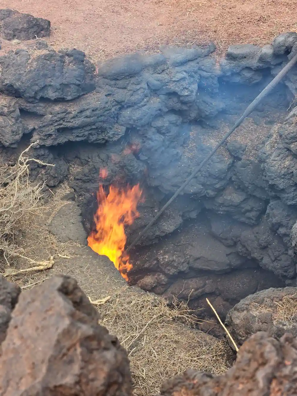 Flames burning from ground rocks in volcanic landscape area