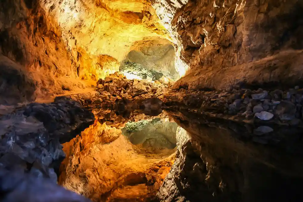 Golden cave interior with water reflection and rock formations