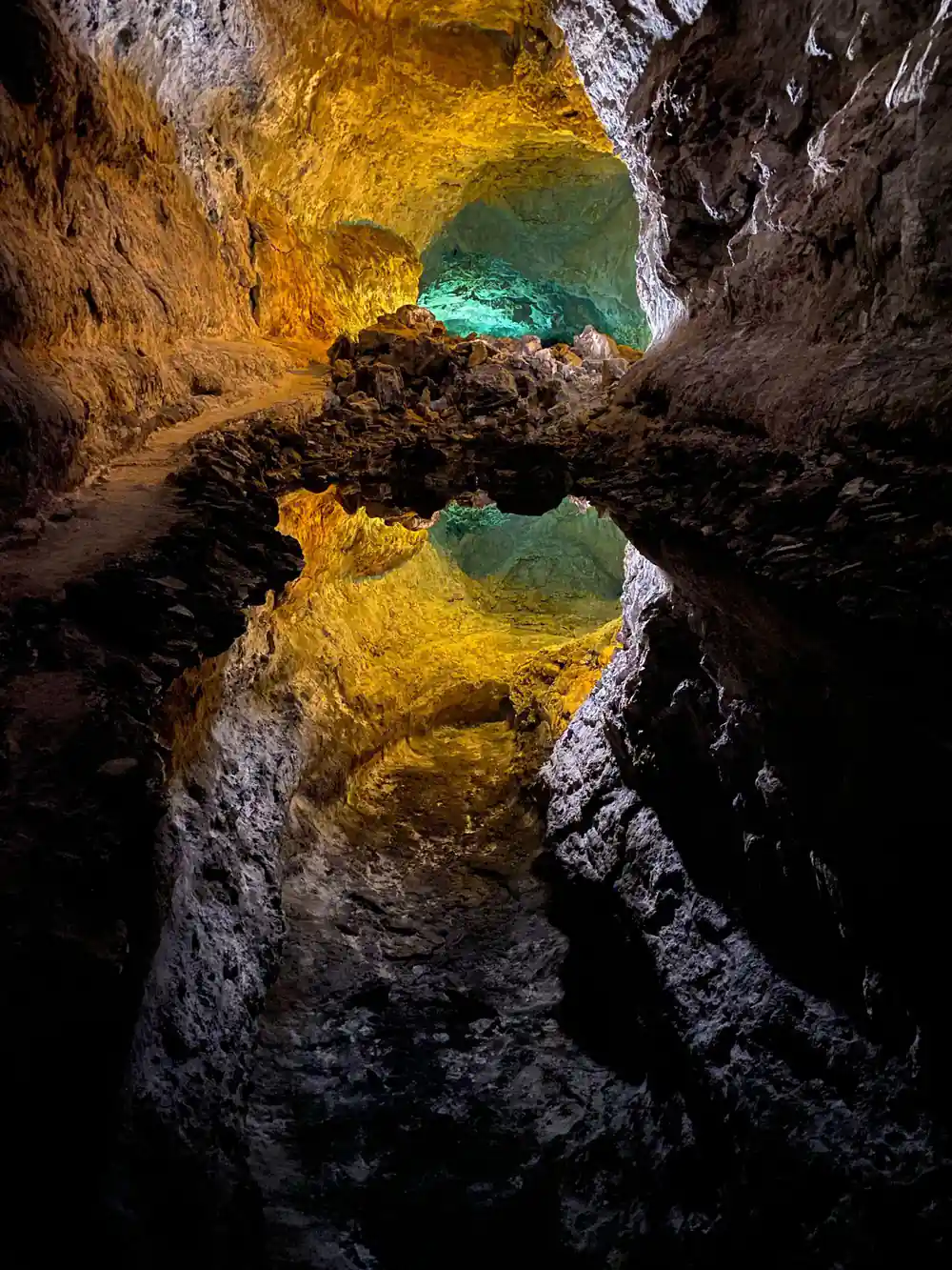Golden-lit underwater cave passage with turquoise water