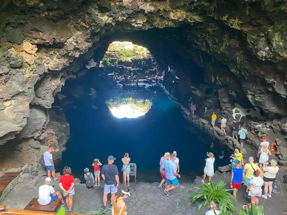 Large cave chamber with bright opening, visitors standing inside