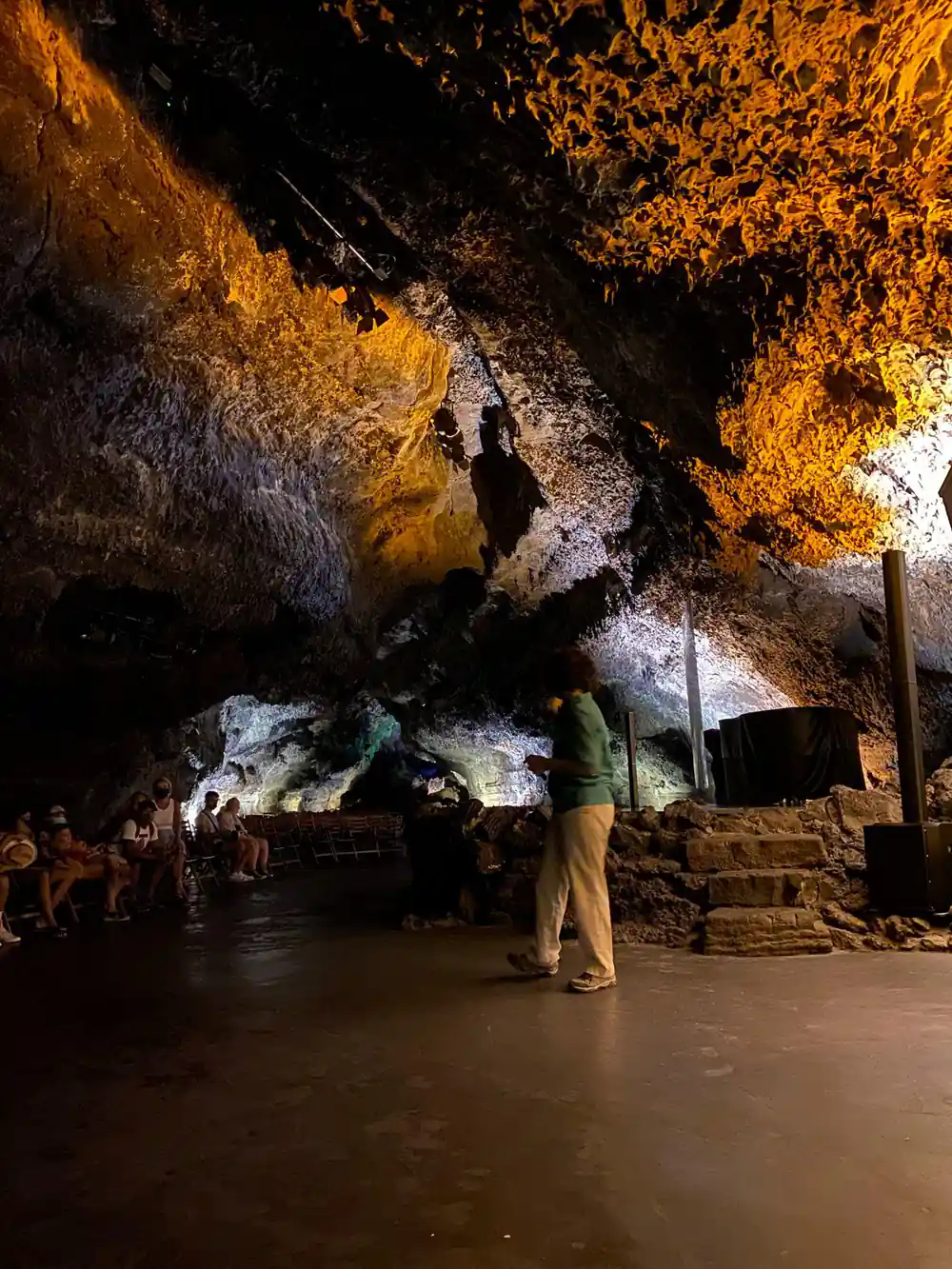 Large cave interior with golden ceiling and tourists standing