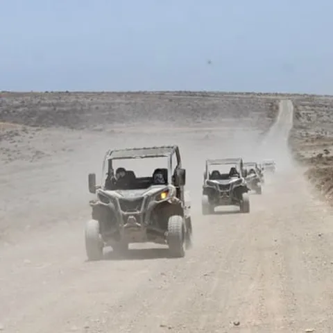 Off-road buggies driving along a dusty volcanic track