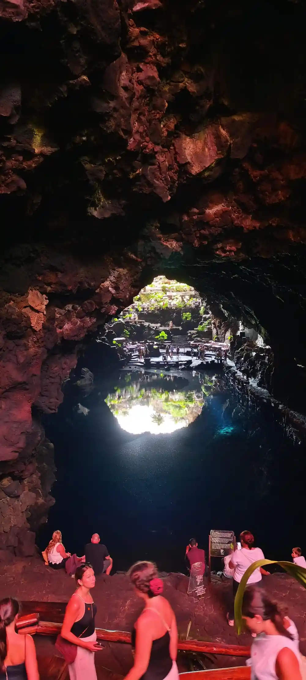People bathing in cavern with bright turquoise illuminated water