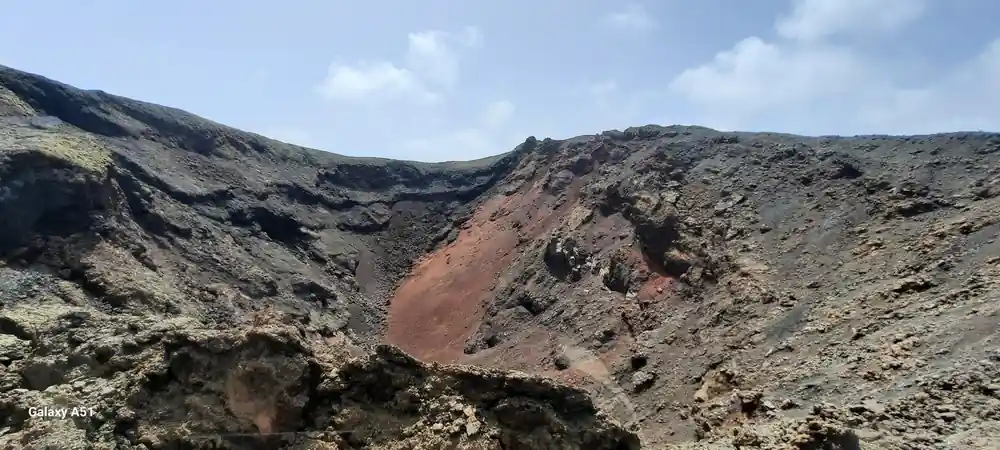 Red volcanic crater crater rim against dark lava landscape