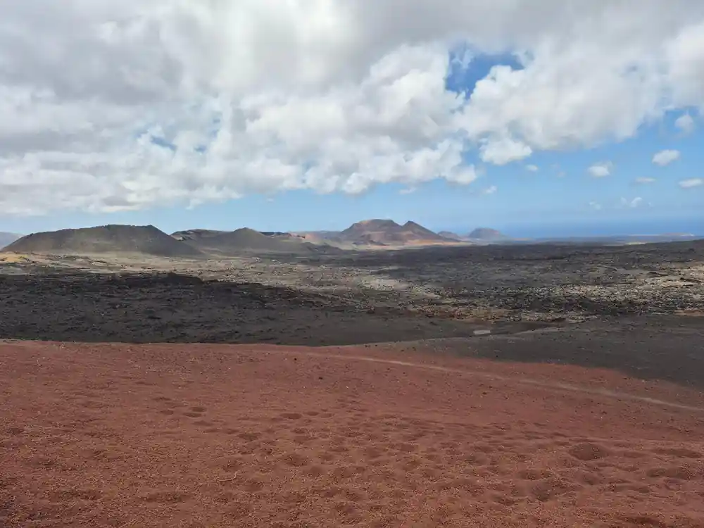 Red volcanic soil landscape with distant volcanic cones