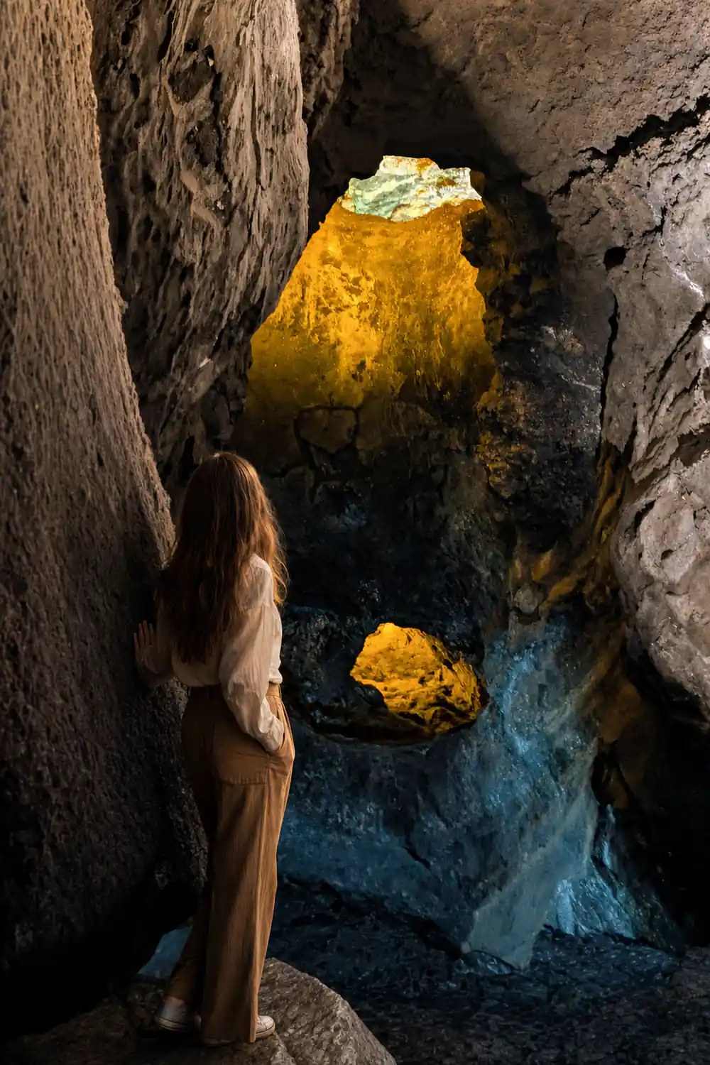 Rock tunnel opening with yellow and green mineral deposits inside