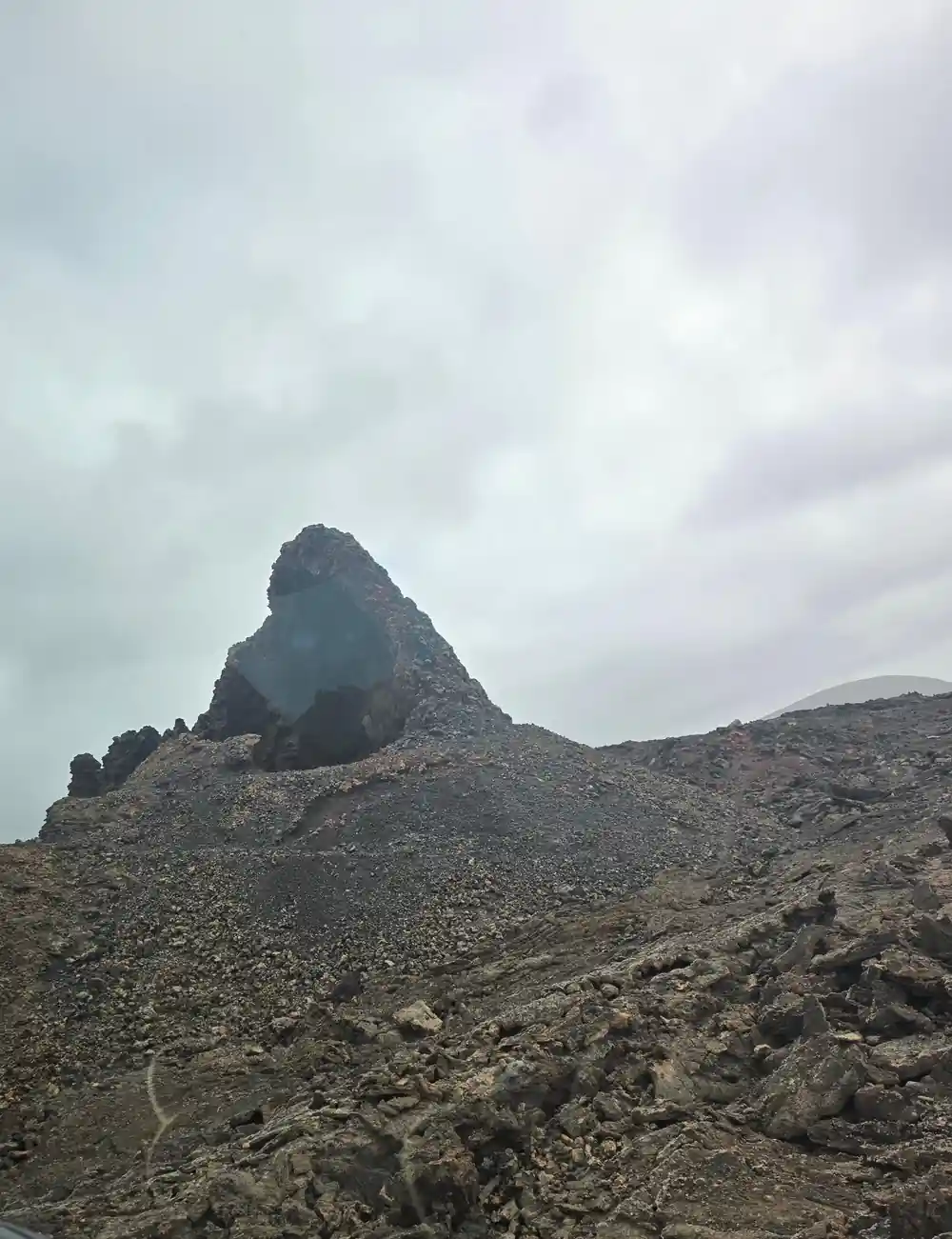 Rocky volcanic peak on barren grey hillside
