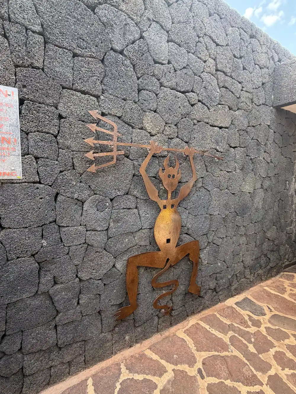 Rust-colored carved figure on dark volcanic stone wall