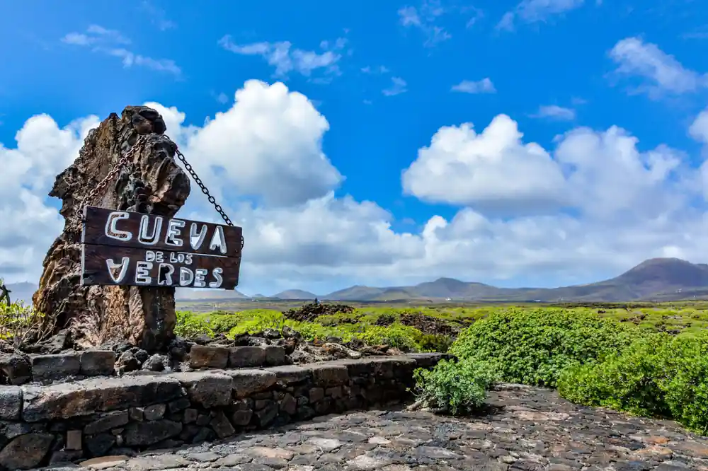 Stone sign reading Cueva de los Verdes in volcanic landscape