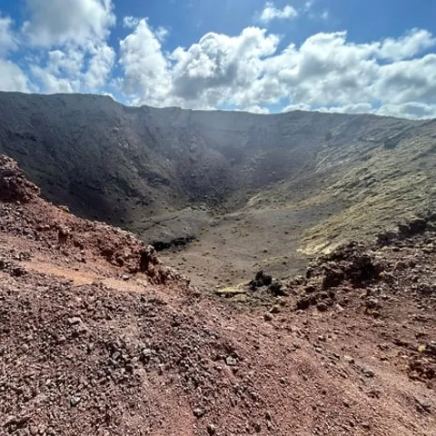 A red volcanic crater seen from its rim on a Timanfaya hike