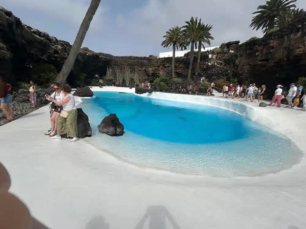 Turquoise lagoon in volcanic crater with palm tree and people
