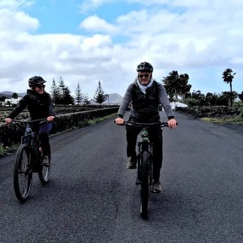 Two e-bike riders on a road between stone walls