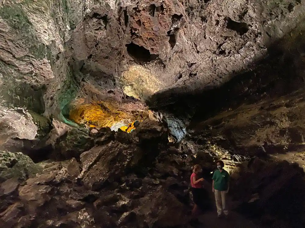 Two people exploring inside a cave with golden lighting