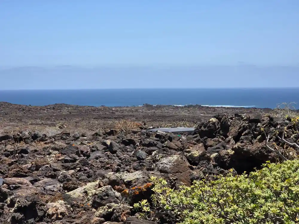 Volcanic lava field sloping toward ocean horizon